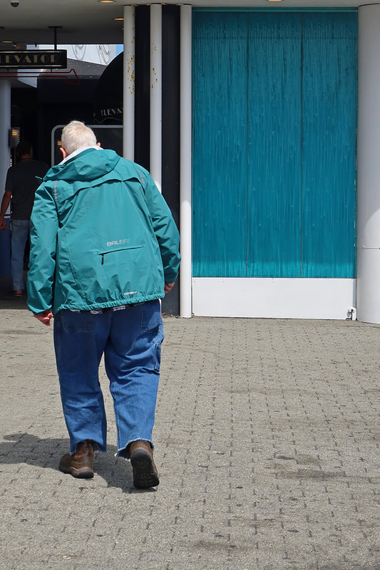 man with turquoise jacket walking through turquoise doorway 