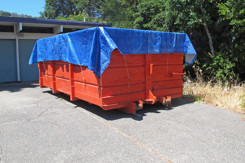 dumpster with blue tarp