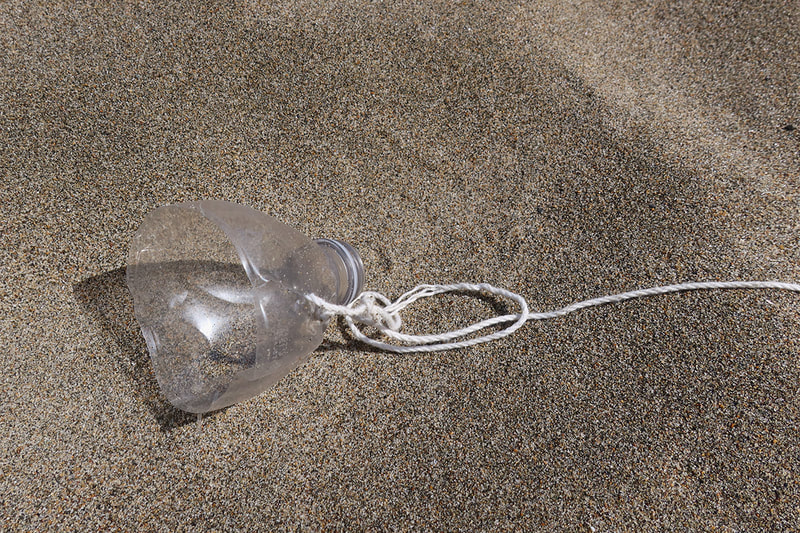 cut bottle with string attached on sand
