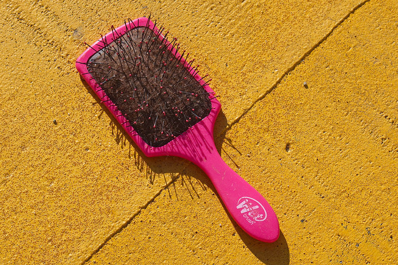 pink hair brush on yellow pavement