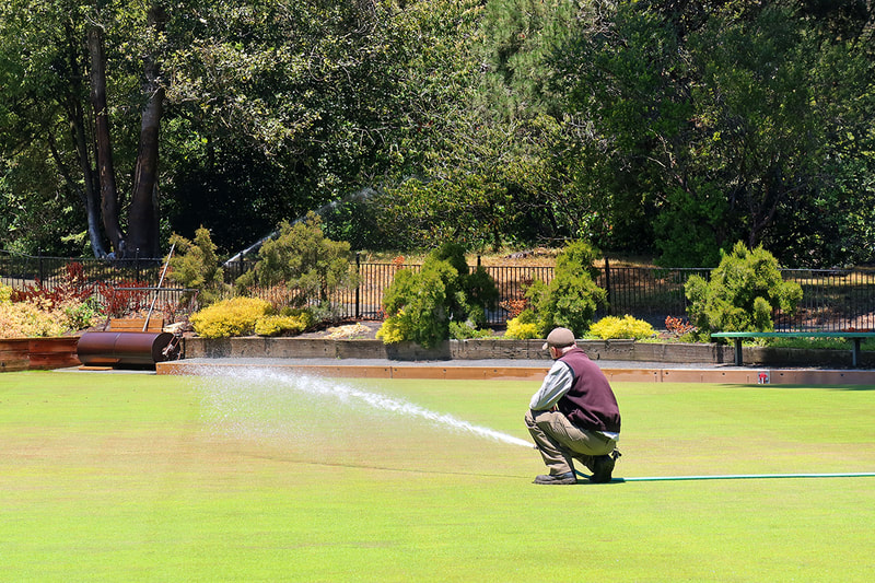 man watering lawn in park 