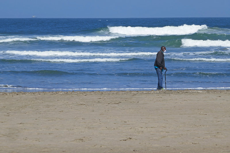 man walking on beach with cane
